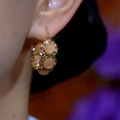 Model showcasing the dangle and style of the 14K Gold-Plated Cat's Eye Stone Diamond Hoop Earrings