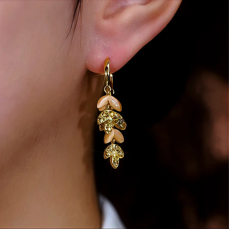 Model showcasing the dangle and style of the 14K Gold-Plated Cat's Eye Stone Diamond Leaf Tassel Earrings