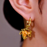 Gold maple leaf hoop drop earring with orange cat's eye stones worn on ear