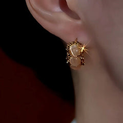 Model showcasing the dangle and style of the 14K Gold-Plated Cat's Eye Stone Little Hoop Earrings