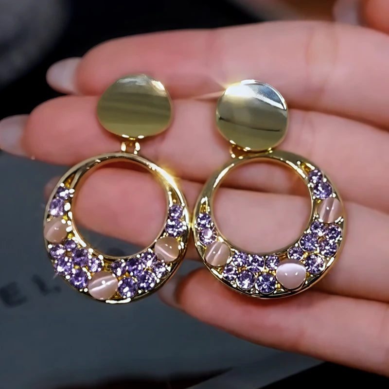 Model showcasing the dangle and style of the 14K Gold-Plated Cat's Eye Stone Purple Diamond Hoop Tassel Earrings