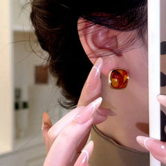 Side view of amber swirl square gold stud earring worn on ear