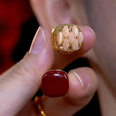 Double-sided huggie earring held in hand, red gem and cream marquise gold sides shown
