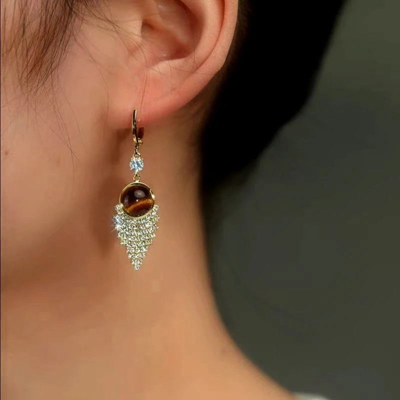 Model showcasing the dangle and style of the 14K Gold-Plated Classic Brown Water Drop Tassel Earrings