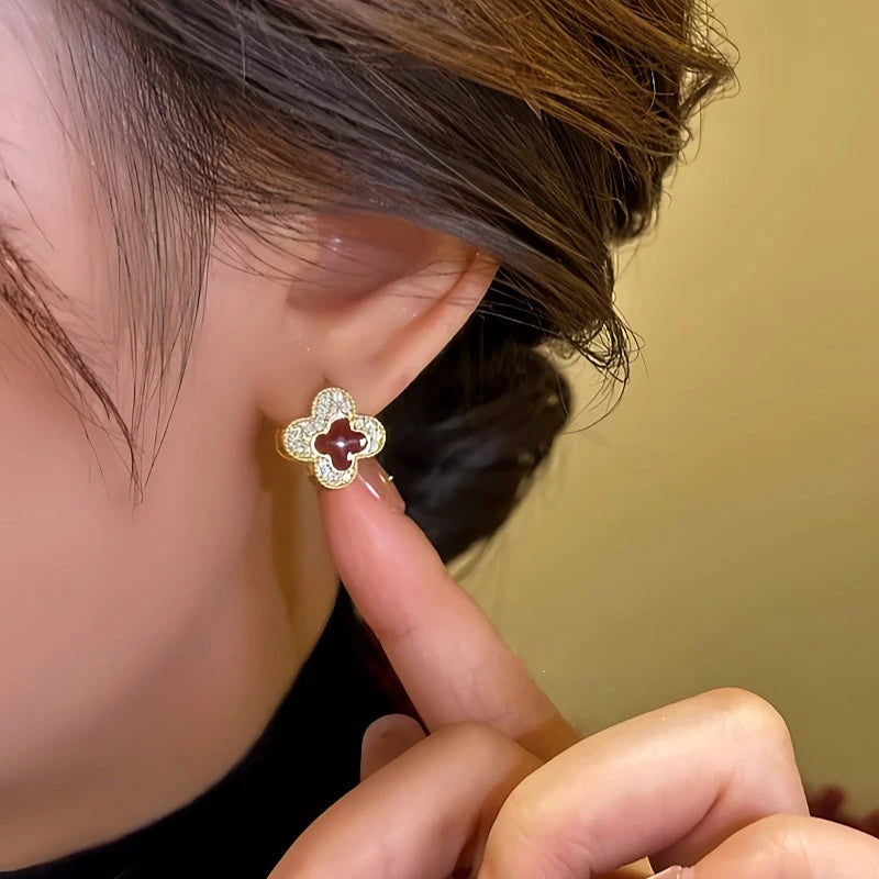 Model showcasing the dangle and style of the 14K Gold-Plated Contrasting Printed Clover Earrings