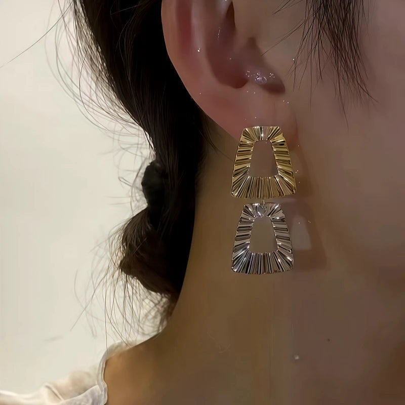 Model showcasing the dangle and style of the 14K Gold-Plated Contrasting Square Stitching Earrings