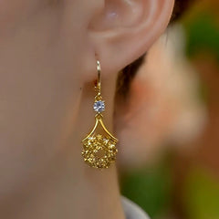 Model showcasing the dangle and style of the 14K Gold-Plated Diamond-Studded Brown Water Drop Tassel Earrings