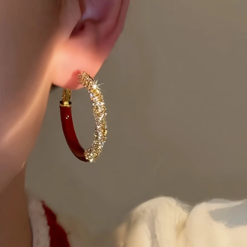 Model showcasing the dangle and style of the 14K Gold-Plated Diamond-Studded Red Glaze Hoop Earrings