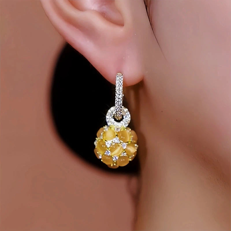 Model showcasing the dangle and style of the 14K Gold-Plated Diamond Cat's Eye Ball Earrings
