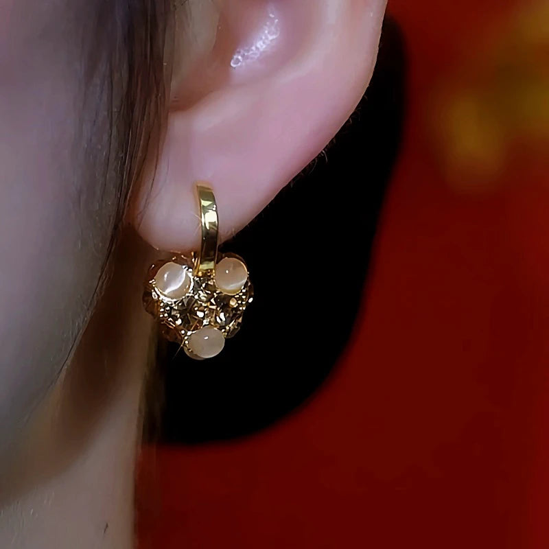 Model showcasing the dangle and style of the 14K Gold-Plated Diamond Cat's Eye Stone Heart Earrings