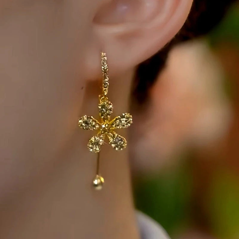Model showcasing the dangle and style of the 14K Gold-Plated Diamond Flower Earrings