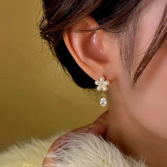 Model showcasing the dangle and style of the 14K Gold-Plated Diamond Flower Earrings