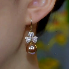 Model showcasing the dangle and style of the 14K Gold-Plated Diamond Flower Pearl Earrings
