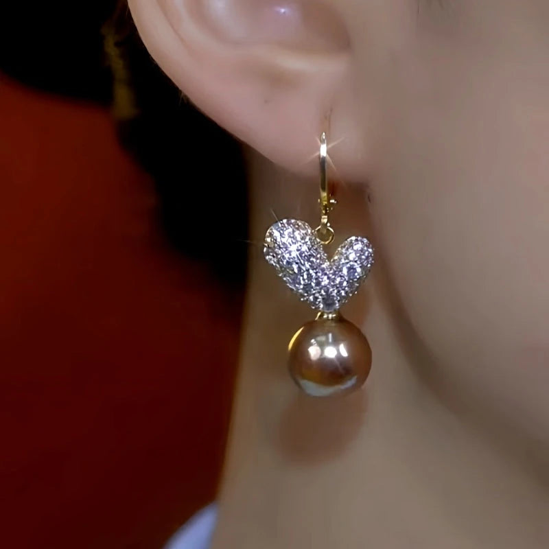 Model showcasing the dangle and style of the 14K Gold-Plated Diamond Heart Brown Pearl Earrings