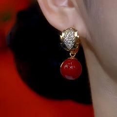 Model showcasing the dangle and style of the 14K Gold-Plated Diamond Leaf Red Pearl Earrings