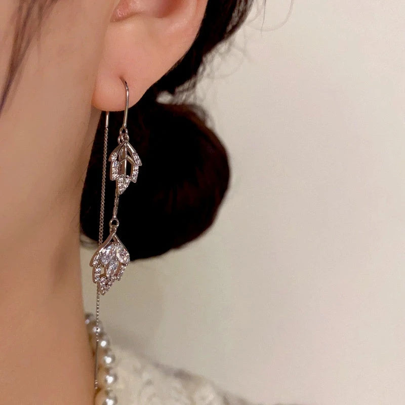 Model showcasing the dangle and style of the 14K Gold-Plated Diamond Leaf Threader Tassel Earrings