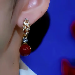 Model showcasing the dangle and style of the 14K Gold-Plated Diamond Red Pearl Earrings