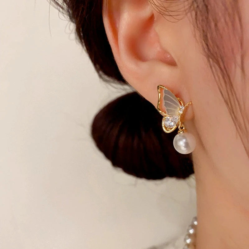 Model showcasing the dangle and style of the 14K Gold-Plated Diamond Shell Butterfly Pearl Earrings