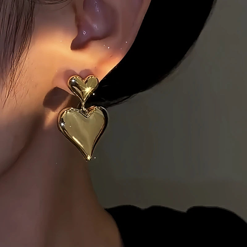 Model showcasing the dangle and style of the 14K Gold-Plated Double-Heart Earrings