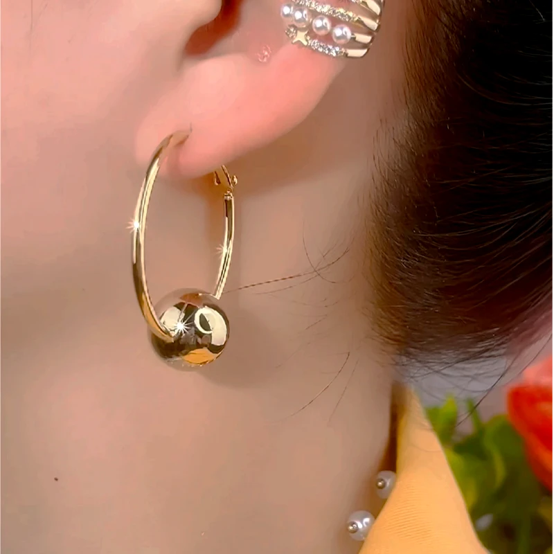 Model showcasing the dangle and style of the 14K Gold-Plated Elegant Ball Hoop Earrings