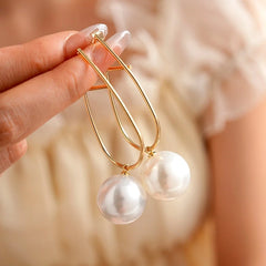 Model showcasing the dangle and style of the 14K Gold-Plated Elegant Bead Pearl Earrings