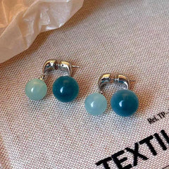 Model showcasing the dangle and style of the 14K Gold-Plated Elegant Cat's Eye Ball Cross Earrings