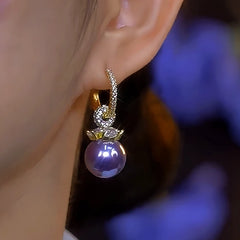 Model showcasing the dangle and style of the 14K Gold-Plated Elegant Diamond-Studded Purple Pearl Earrings