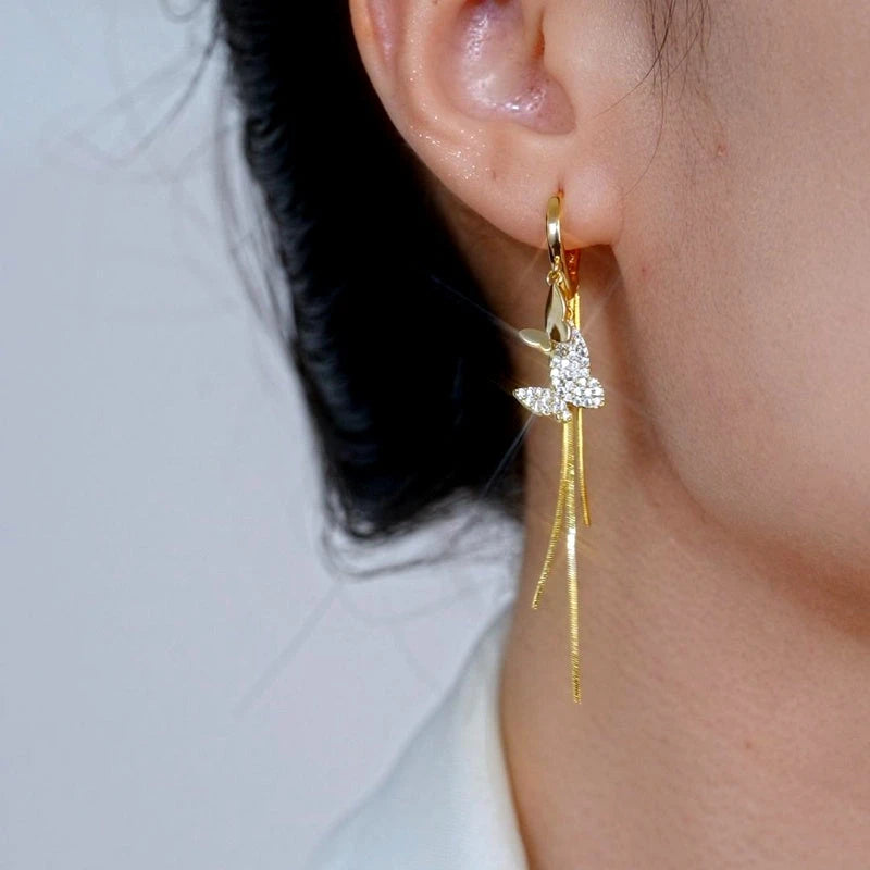 Model showcasing the dangle and style of the 14K Gold-Plated Elegant Double-Butterfly Tassel Earrings