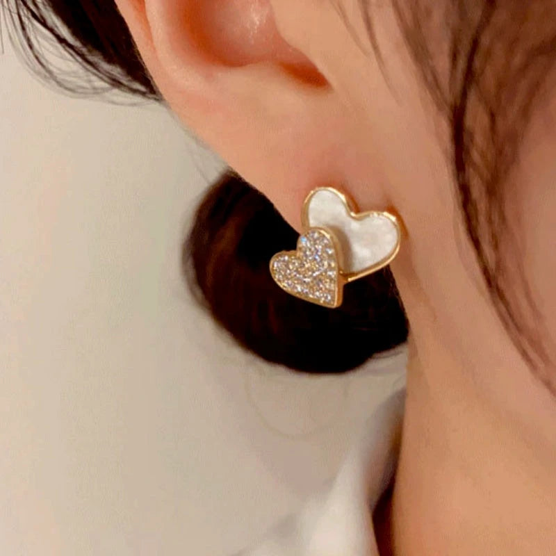 Model showcasing the dangle and style of the 14K Gold-Plated Elegant Double Heart Stud Earrings