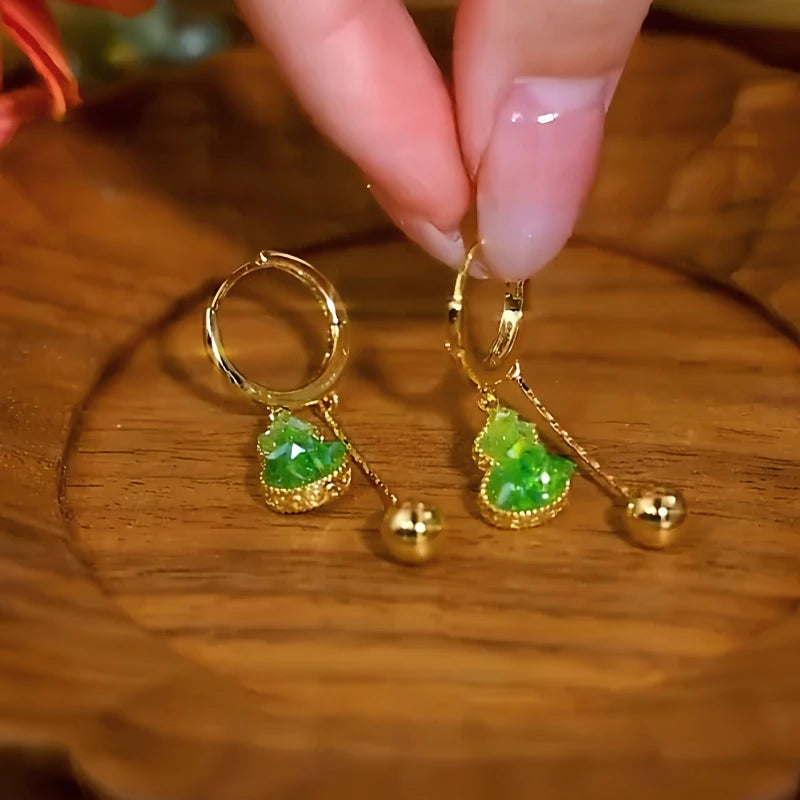 Angled view of the 14K Gold-Plated Elegant Green Crystal Gourd Tassel Earrings
