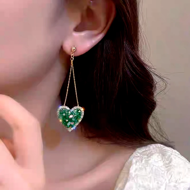 Angled view of the 14K Gold-Plated Elegant Green Rhinestone Heart Tassel Earrings
