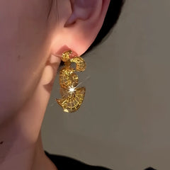 Model showcasing the dangle and style of the 14K Gold-Plated Elegant Hollow Wave Hoop Earrings