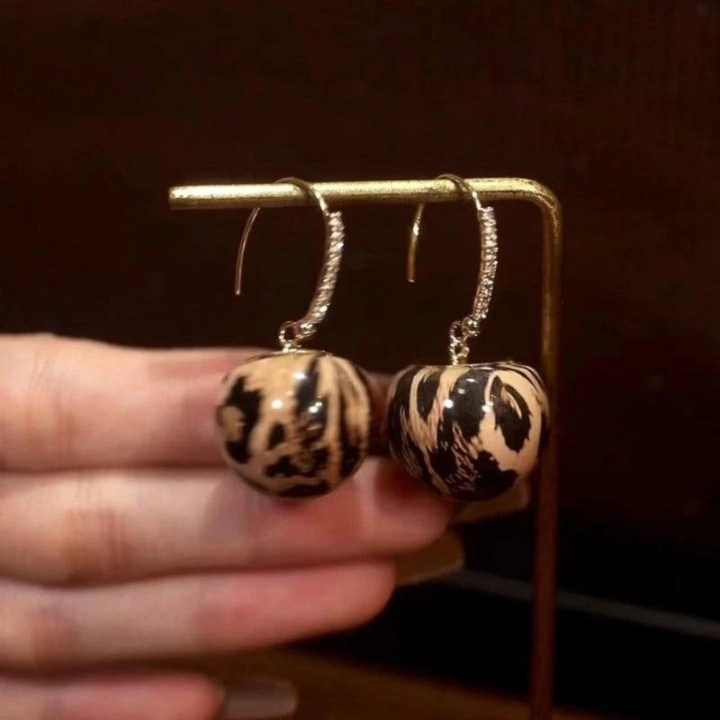 Model showcasing the dangle and style of the 14K Gold-Plated Elegant Leopard Print Ball Ear Hooks