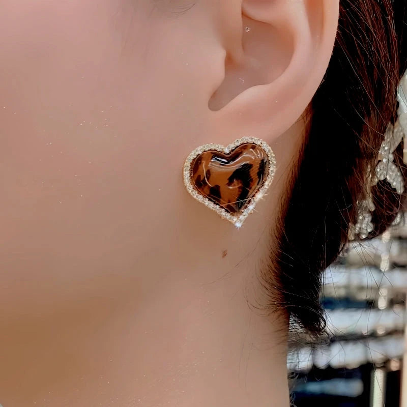 Model showcasing the dangle and style of the 14K Gold-Plated Elegant Leopard Print Heart Earrings