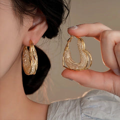 Model showcasing the dangle and style of the 14K Gold-Plated Elegant Mesh Heart-Design Earrings
