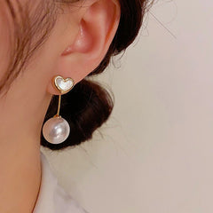Model showcasing the dangle and style of the 14K Gold-Plated Elegant Mother-Of-Pearl Heart Earrings