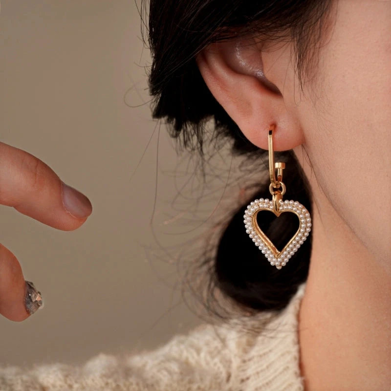Model showcasing the dangle and style of the 14K Gold-Plated Elegant Pearl Heart Earrings