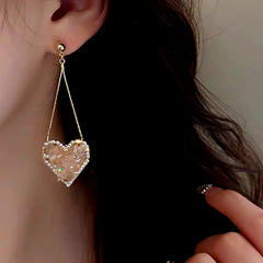 Model showcasing the dangle and style of the 14K Gold-Plated Elegant Pink Rhinestone Heart Tassel Earrings