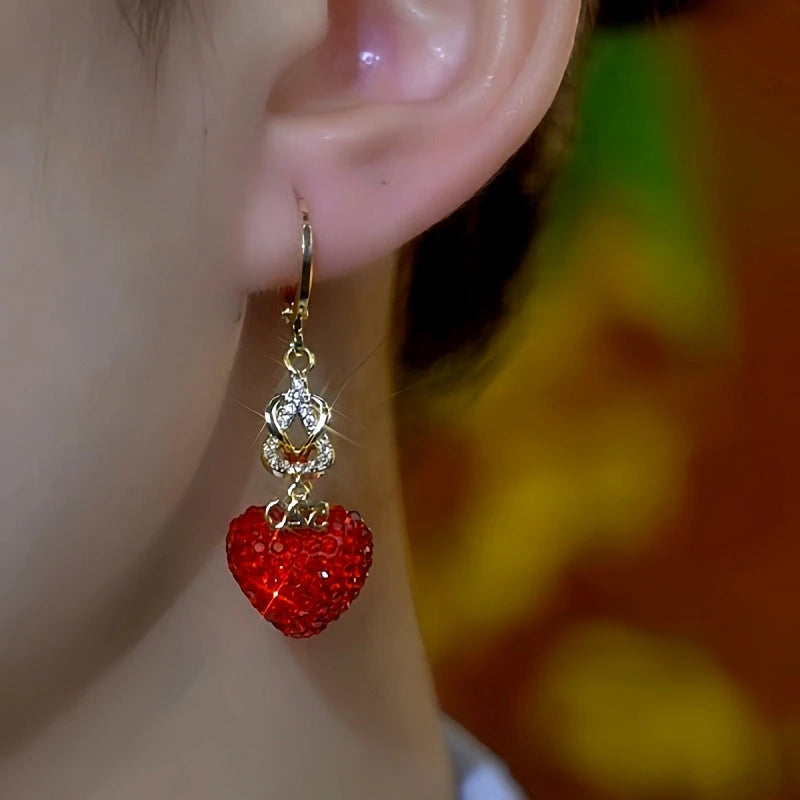 Model showcasing the dangle and style of the 14K Gold-Plated Elegant Red Diamond Heart Earrings