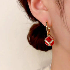 Model showcasing the dangle and style of the 14K Gold-Plated Elegant Red Zircon Cube Earrings