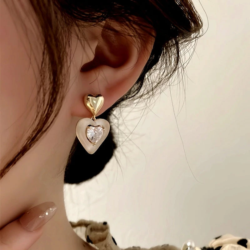 Model showcasing the dangle and style of the 14K Gold-Plated Elegant Rhinestone Heart Earrings