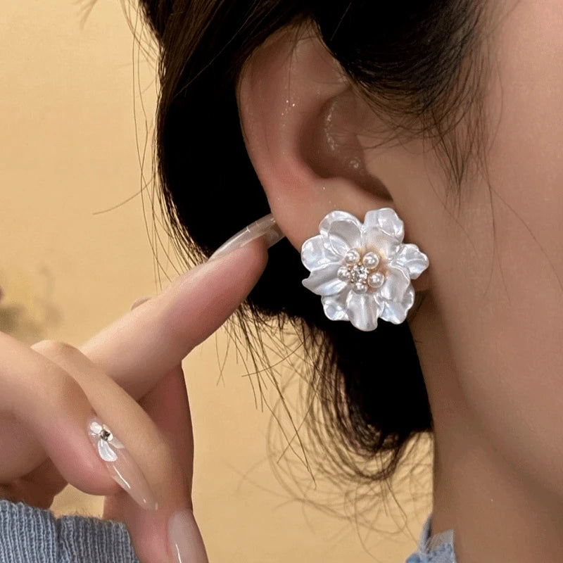 Model showcasing the dangle and style of the 14K Gold-Plated Elegant Shall Flower Pearl Stud Earrings
