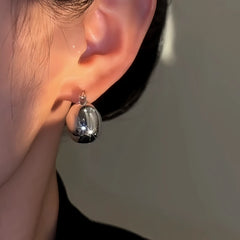 Model showcasing the dangle and style of the 14K Gold-Plated Elegant Silver Bag Earrings