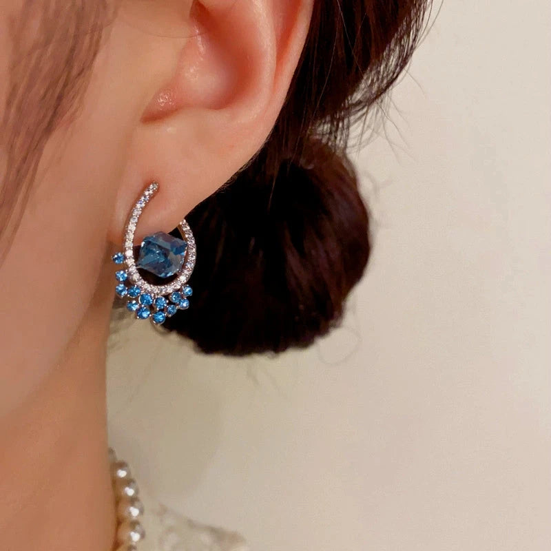 Model showcasing the dangle and style of the 14K Gold-Plated Elegant U-Shaped Blue Diamond Earrings