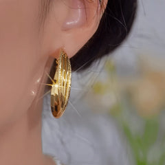 Model showcasing the dangle and style of the 14K Gold-Plated Elegant Winding Hoop Earrings