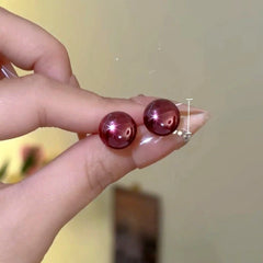 Model showcasing the dangle and style of the 14K Gold-Plated Elegant Wine Red Bead Stud Earrings
