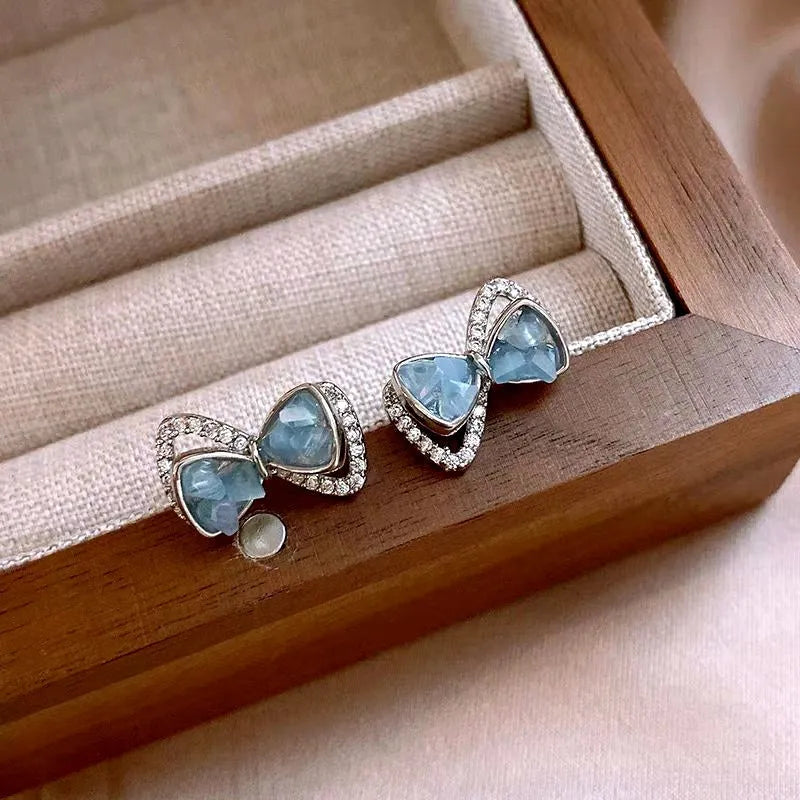 Model showcasing the dangle and style of the 14K Gold-Plated Elegant Zircon Blue Crystal Bow Stud Earrings