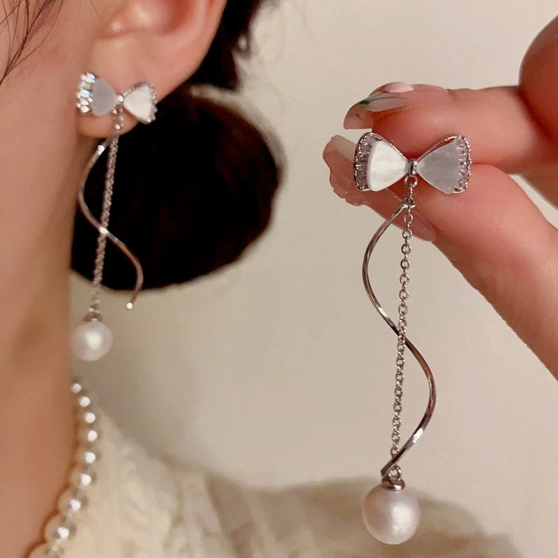 Model showcasing the dangle and style of the 14K Gold-Plated Elegant Zircon Bow Pearl Tassel Earrings