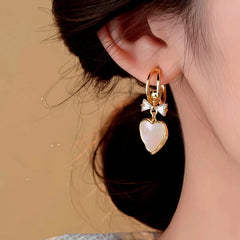 Model showcasing the dangle and style of the 14K Gold-Plated Elegant Zircon Bow Shell Heart Earrings