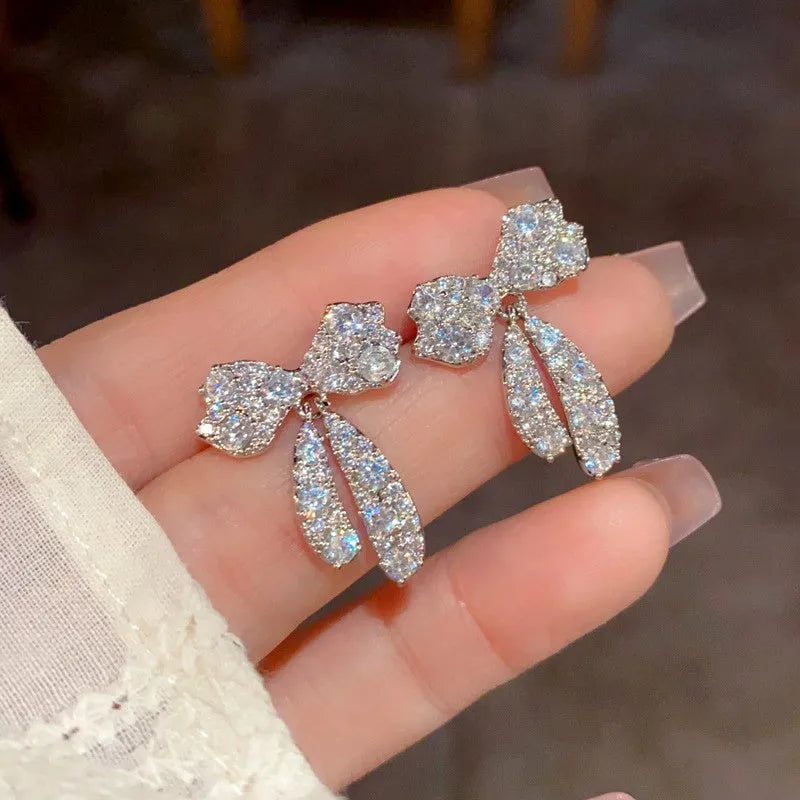 Model showcasing the dangle and style of the 14K Gold-Plated Elegant Zircon Bow Tassel Earrings